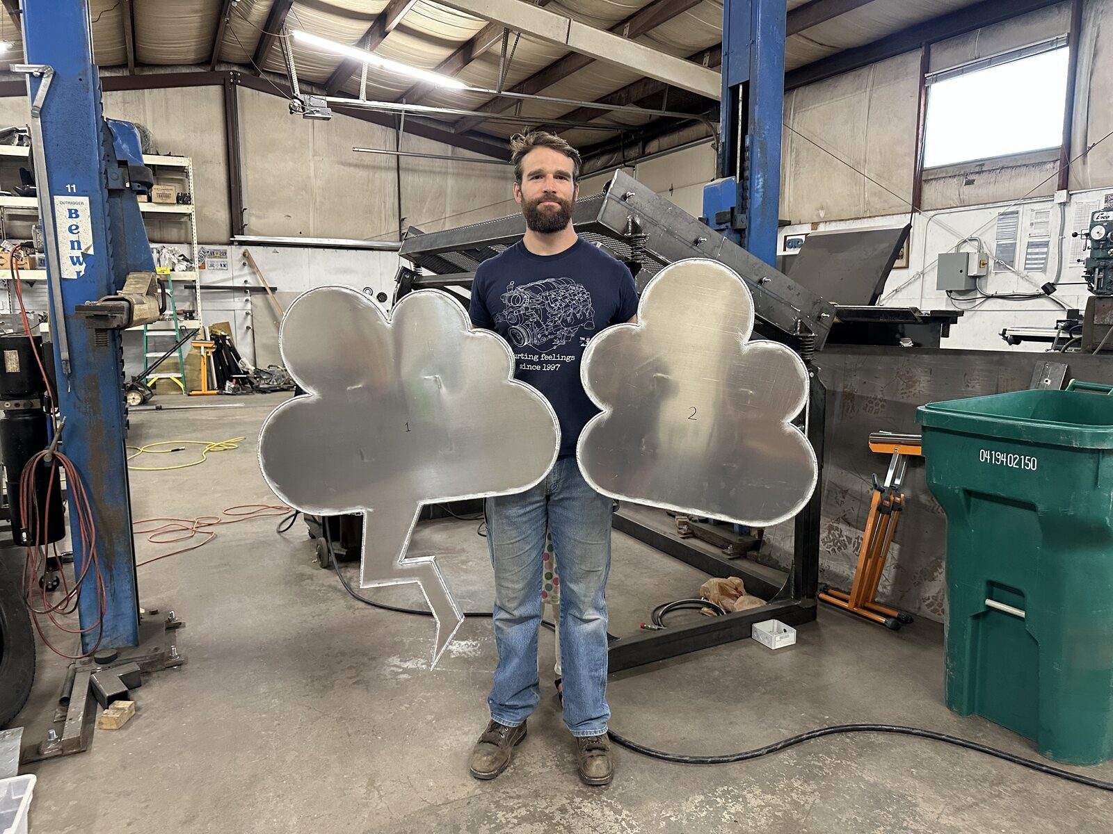 Mark in the shop holding two finished aluminum clouds